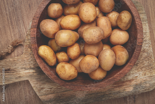 Freshly harvested small potatoes in a wooden bowl on a rustic cutting board ready for cooking