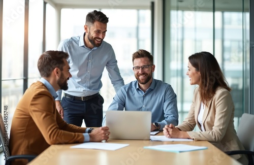 Successful business team informal meeting at office. Group of diverse professionals at table, using laptop. Happy colleagues discuss project, smiling. Authentic moment of teamwork. Positive