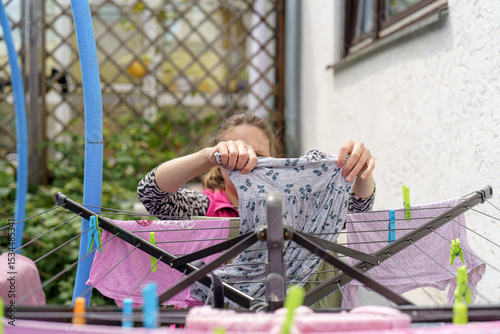 Drying laundry outdoors in a garden setting while enjoying sunny weather in a quiet neighborhood