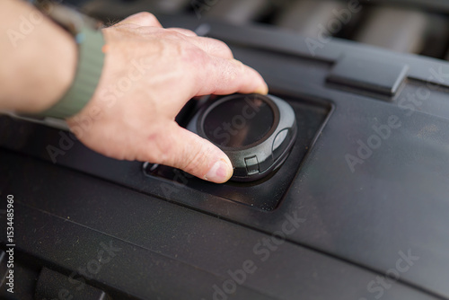 Hand adjusts control on engine compartment during routine maintenance at workshop in the afternoon hours
