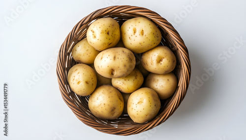 Wicker bowl with raw potatoes on white table