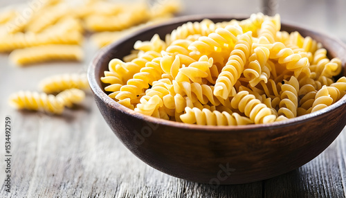 Bowl of raw fusilli pasta isolated on white background
