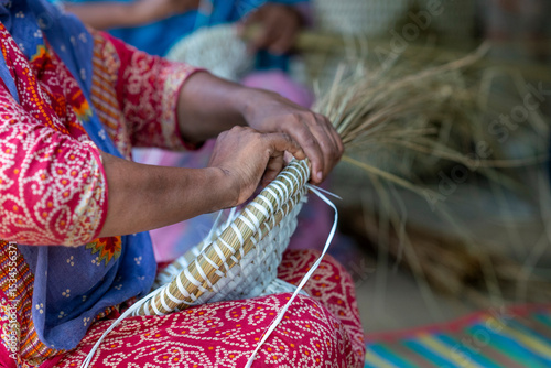 Woman Weaving a Basket with Natural materials. Hands weaving a straw basket. Ancient Indian's hand making a basket with leaf's of palm trees. 
