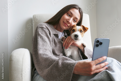 Young woman taking selfies with her dog. Copy space, background.