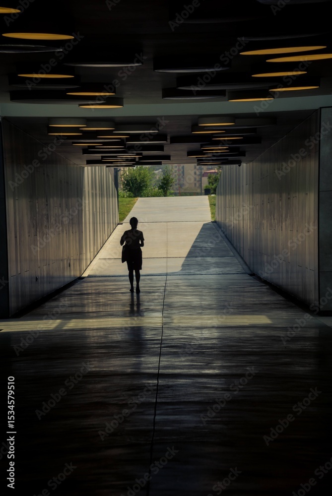 Fototapeta premium Silhouette of a woman walking in a tunnel