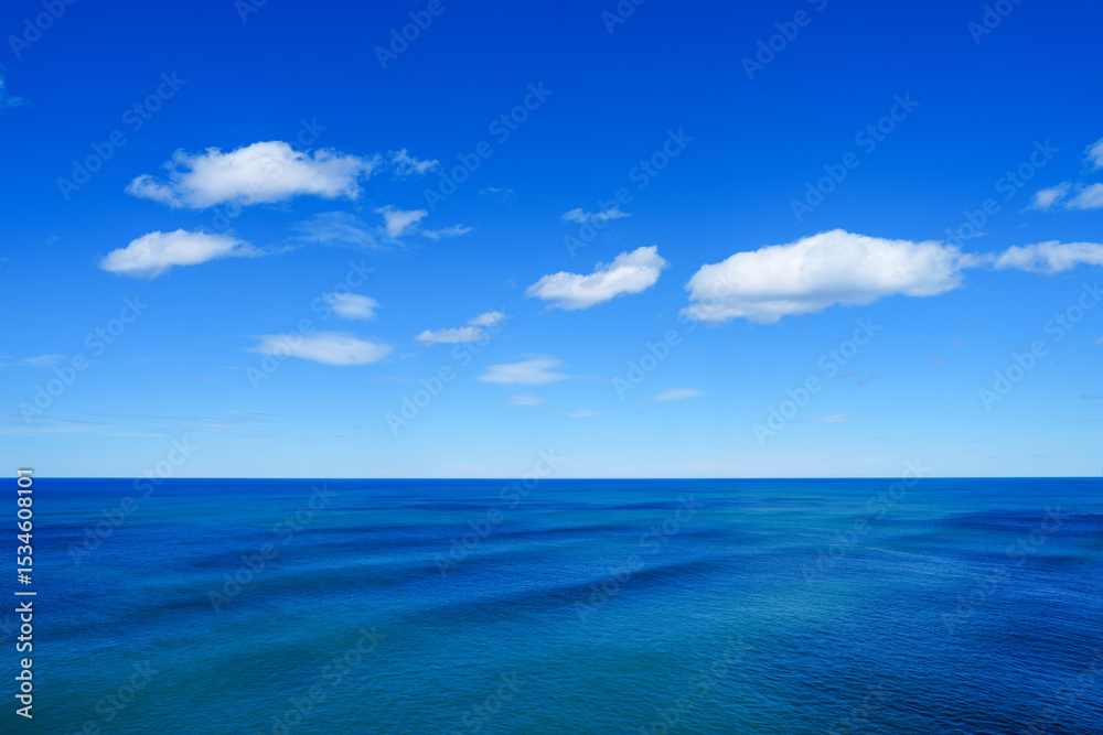 Fototapeta premium Bright blue ocean horizon with fluffy clouds
