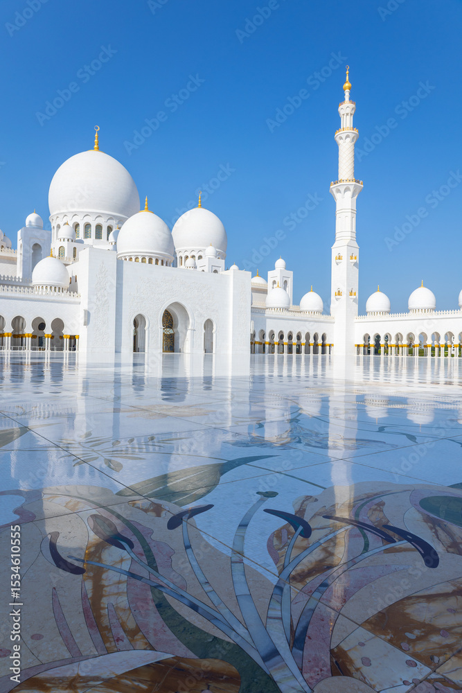 Obraz premium View of Sheikh Zayed Grand Mosque in Abu Dhabi made of white marble with flowers made of precious stones in design and beautiful reflections. Vertical photo