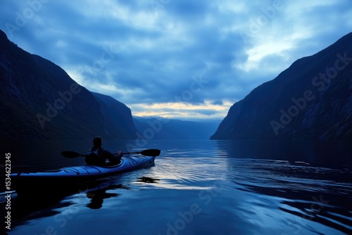 A lone kayaker paddles through a serene fjord under a cloudy, twilight sky, surrounded by majestic mountains, creating a tranquil and adventurous scene.