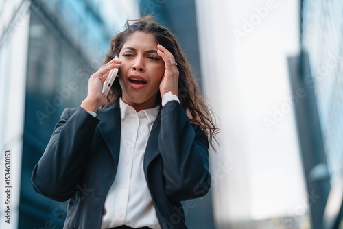 Tableau sur toile Businesswoman expressing frustration while talking on a phone outside modern sky