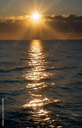 Golden hour sunset over sparkling ocean waves with a stunning sunburst.