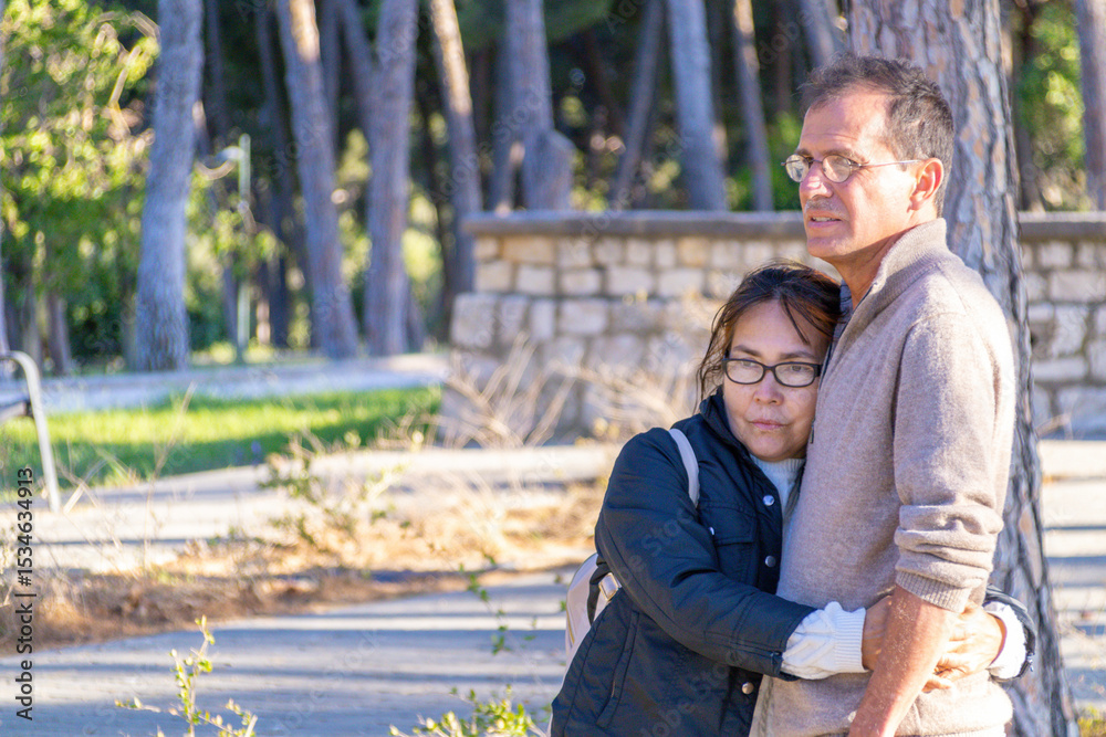 Fototapeta premium Couple sharing a quiet moment in a sunlit park surrounded by tall trees