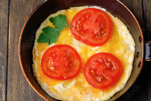 Omelet with tomatoes in a pan on wooden background. Rustic nutrition breakfast. Flat lay. Close up.