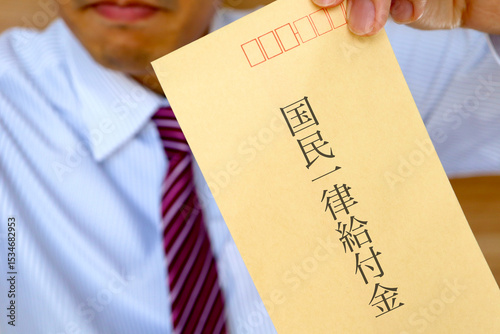 スーツの男性が国民一律給付と書かれた封筒を持っている