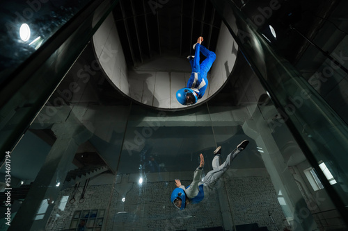 A male instructor teaches a woman how to fly in a wind tunnel. Free fall simulator.