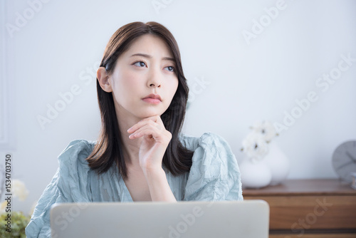 Tapety artystyczne 部屋でパソコンをみて考える悩む迷うかわいい女性 ちょっと真剣なネガティブイメージ 転職どうしようかな～