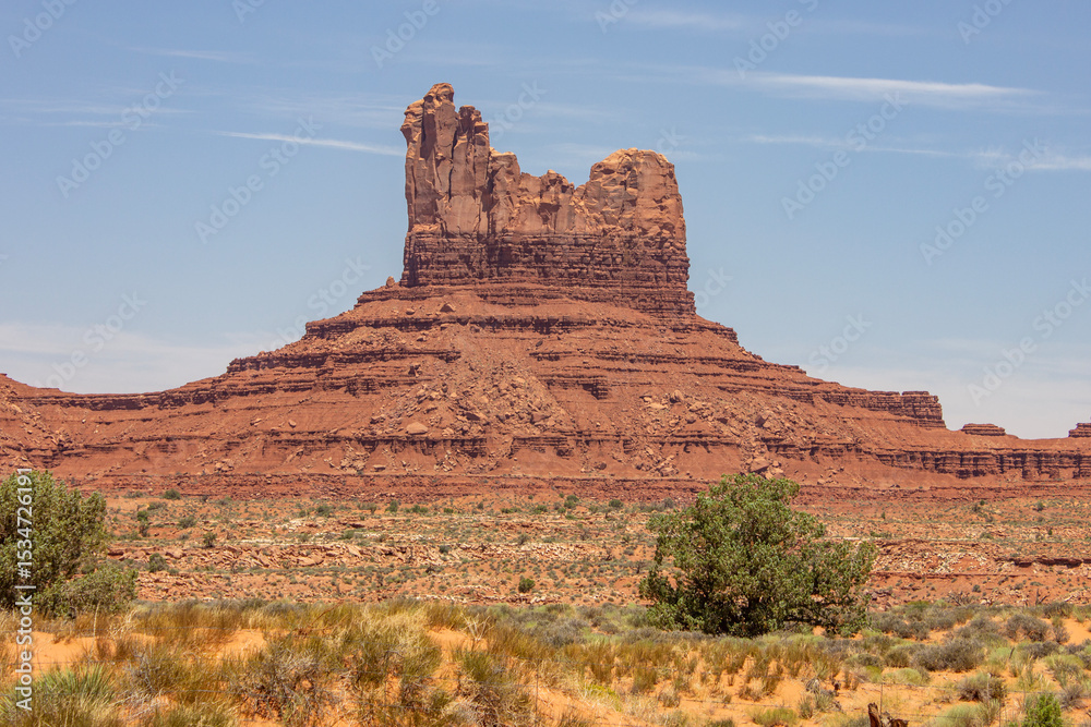 Monument Valley features red rock formations beneath a blue sky in a sunny afternoon landscape in Utah Monument Valley features red rock formations beneath a blue sky in a sunny afternoon landscape in Utah