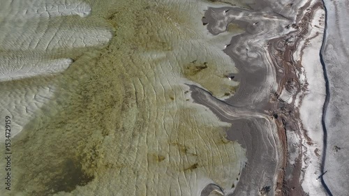 Aerial Great Salt Lake mud shore environment above 2. Largest saltwater lake in the Western Hemisphere. Solar evaporation ponds produce salt, potassium, magnesium. Recreation and industry.