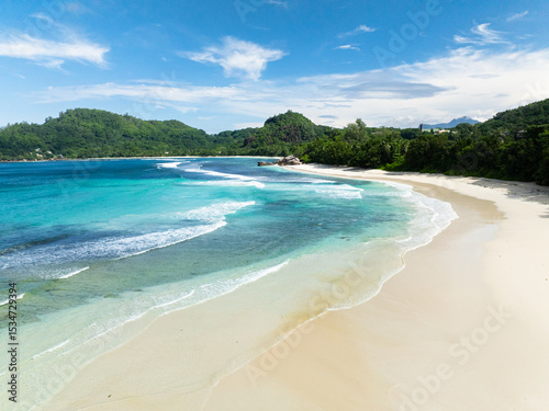 Wide sandy beach with ocean surf and waves. Seychelles, Mahe. Baie Lazare Beach.