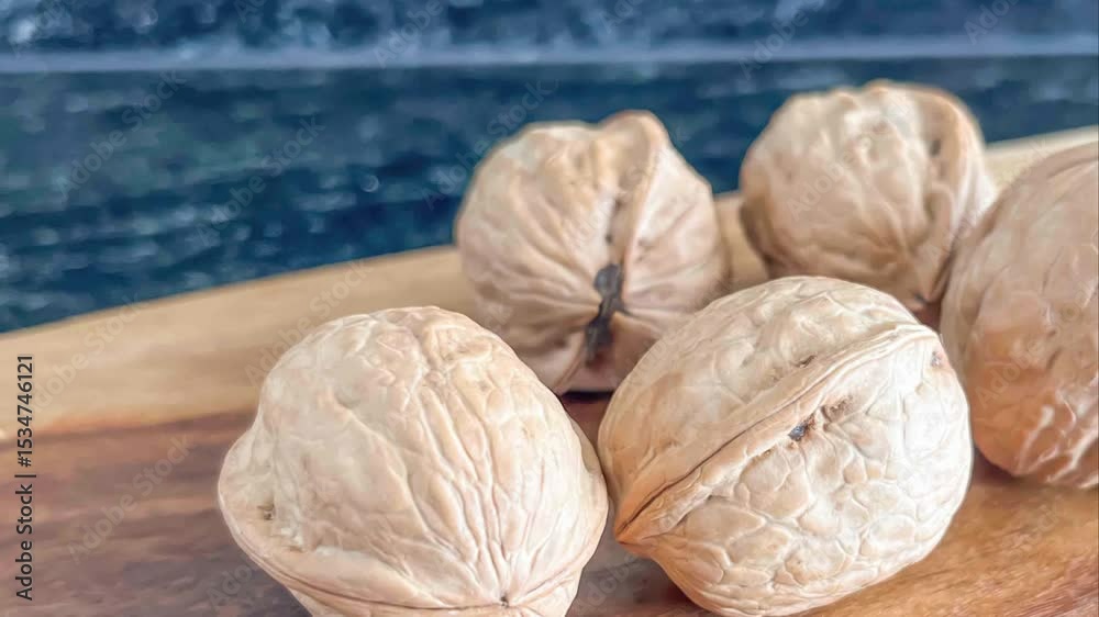 Close up of several walnuts in their shells on a wooden surface with a dark blue background