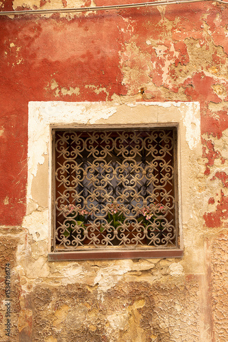 View of a window covered with an ornate and decorative metal security grill, Venice