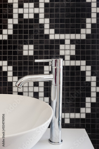 bathroom sink with chrome tap and black and white mosaic tiles