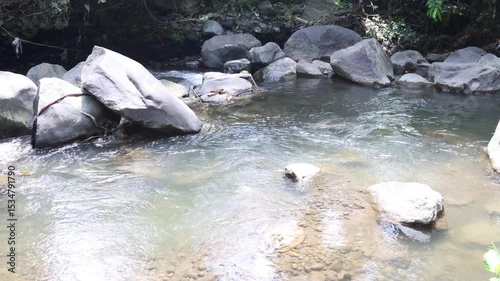 Camera movement over a view of a river with clear water and volcanic rocks