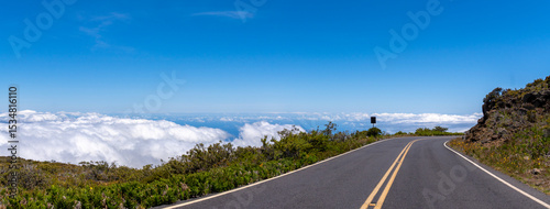 Scenic road above the clouds under a clear blue sky on a sunny day.