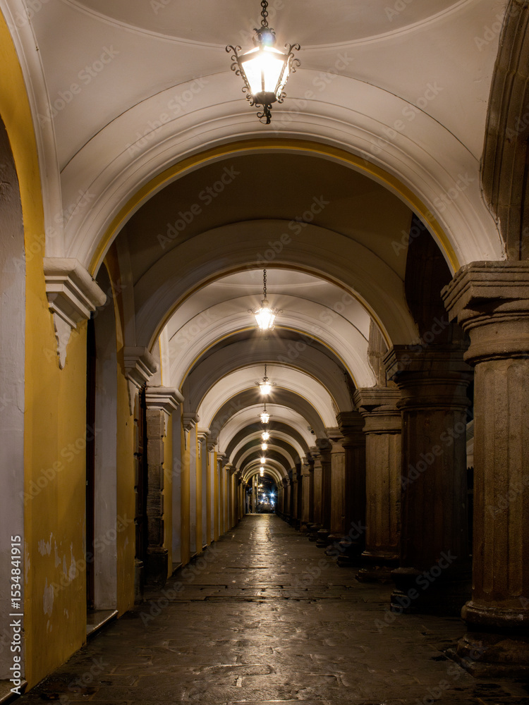 Fototapeta premium Historic stone corridor with arches and lamps in Antigua Guatemala showcasing charming architecture