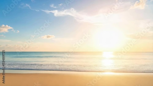 Golden light over calm ocean waves gently lapping on the sandy shore under a clear blue sunny sky with soft clouds, summer beach view