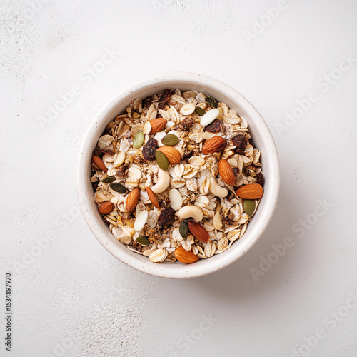 Top-down view of muesli in bowl placed on white surface, rich variety ideal for organic breakfast content or nutrition branding