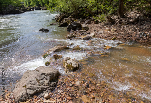 shallow river bottom with a small current in the spring period with various shapes and structures of the riverbed