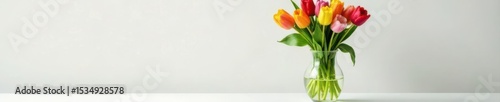 Vibrant tulip & filler arrangement in glass vase, white tabletop, water beads added , detail, simple, vase