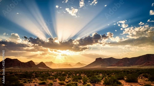Vivid Sunset Over a Rugged Desert Landscape with Mountainous Terrain and Radiant Sunlight Beams Filtering Through Clouds
