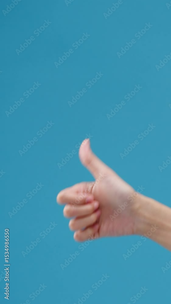 Vertical Screen : Young woman hand showing thumb up sign with fingers isolated over blue background in studio. Copy space for place text, message for advertisement. Advertising area, mock up content. Vertical Screen : Young woman hand showing thumb up sign with fingers isolated over blue background in studio. Copy space for place text, message for advertisement. Advertising area, mock up content.