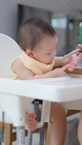 8 month old baby learning to eat for the first time. The concept of a child who has difficulty eating, playing while eating.