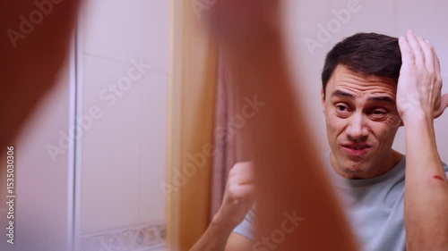 Insecure man combing hair before a date in bathroom mirror