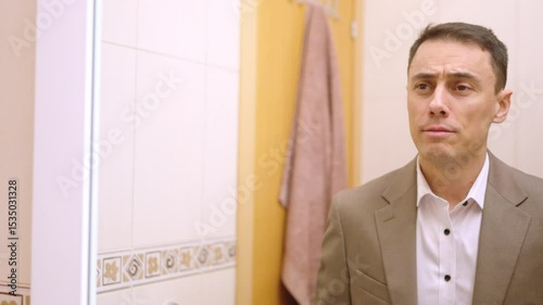 Businessman dressing up and checking himself in bathroom mirror