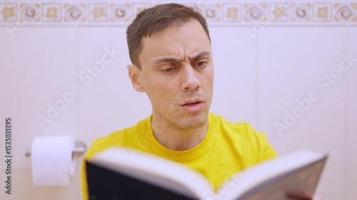 Man reading a book on the toilet