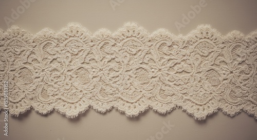 White lace fabric with floral embroidery and scalloped edges laid flat