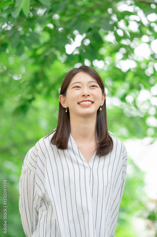 新緑の中に立つ笑顔の女性 新緑の中に立つ笑顔の女性