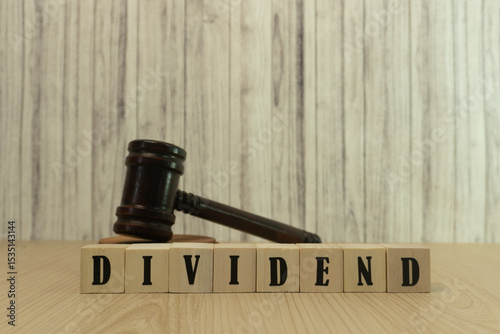 Wooden Blocks Spelling Dividend with a Judge's Gavel Symbolizing Financial Decisions. Dividend growth insights judge's gavel after Annual General Meeting photo