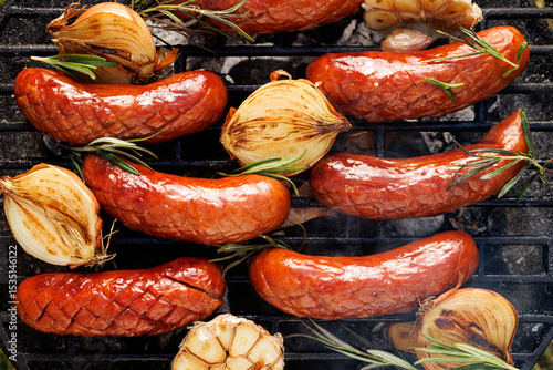 Grilled pork sausages with addition onion and garlic on a cast iron grill,  top view