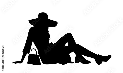 Silhouette of a woman relaxing on the ground with a handbag and hat