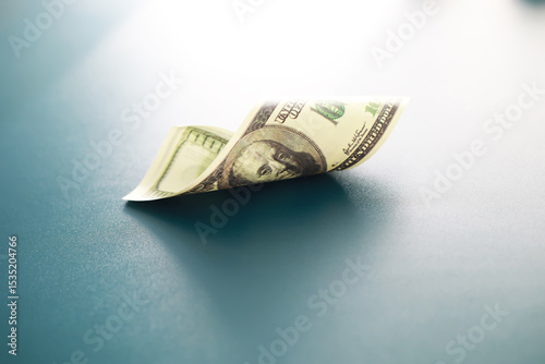 Crisp One Hundred Dollar Bill on Blue Surface in Soft Lighting