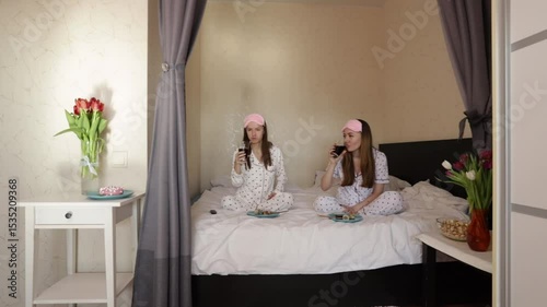 Relaxed weekend morning with girls eating together in bed, surrounded by flowers and snacks.