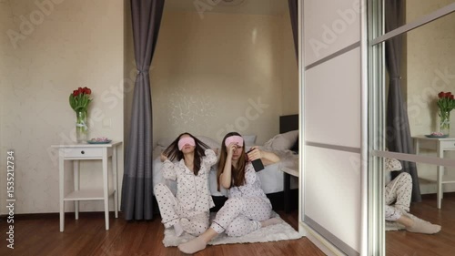Morning moment of friendship as two girls in sleepwear pose for a fun selfie with a bouquet of spring tulips.