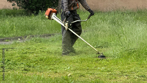 Bild auf Leinwand person using a string trimmer to cut overgrown grass in a green yard