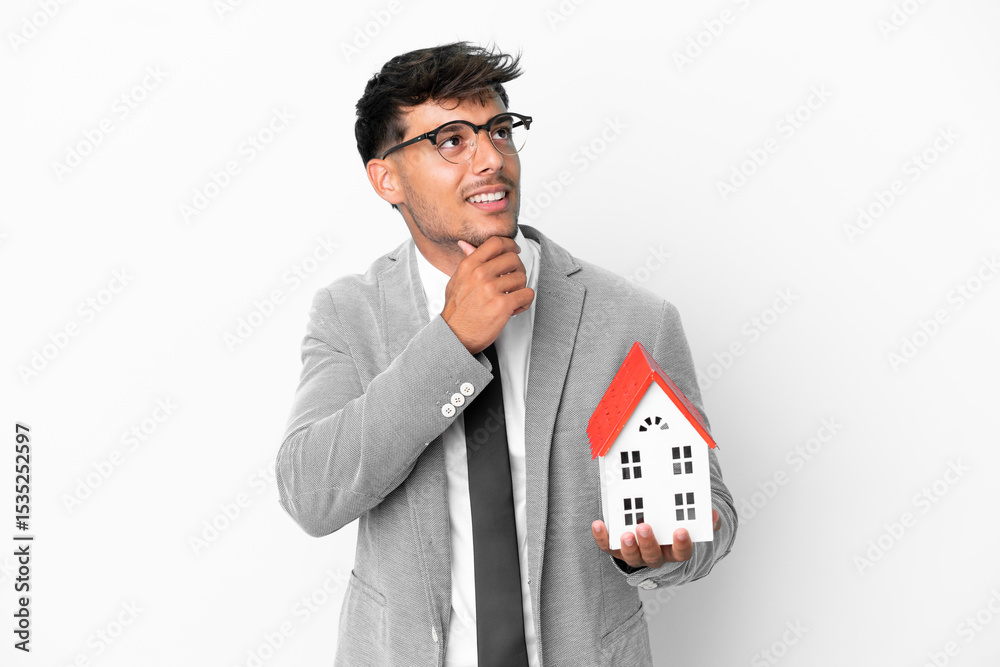 Business man holding a house isolated on blue background and looking up Business man holding a house isolated on blue background and looking up