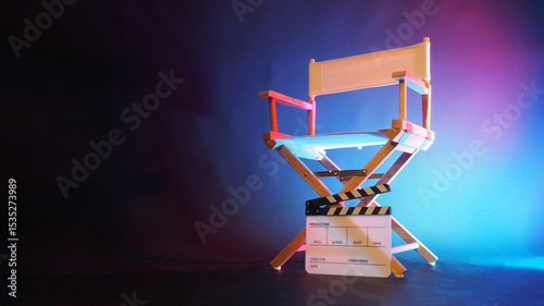 Director chair and black clapper board in carpi blue and pink light.