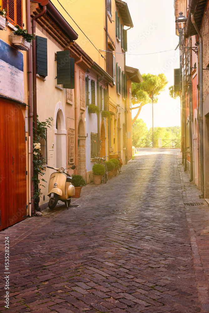 Obraz premium Cobblestone street with scooter and old houses in Rimini, Italy